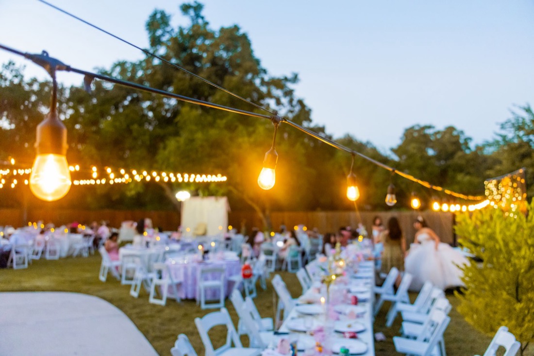 An outdoor wedding reception at dusk under string lights